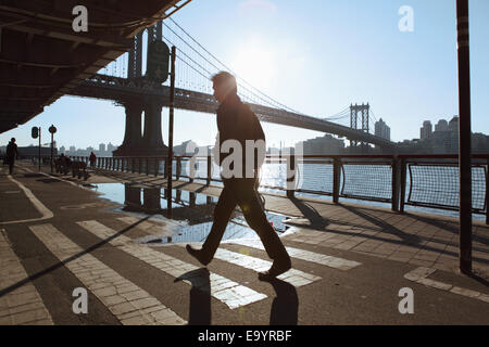 Jeune homme marchant le long de l'East River esplanade par le pont de Manhattan Banque D'Images