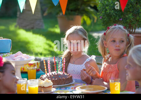 Fille assise à table avec gâteau d'anniversaire Banque D'Images