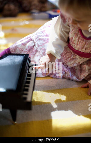 Young Woman sitting on plancher du salon jouer piano jouet boite à musique à Noël Banque D'Images