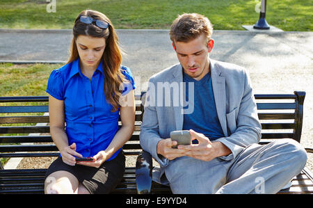 Businessman and woman using smartphone in park Banque D'Images