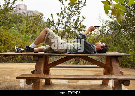 Man using smartphone on table in park Banque D'Images