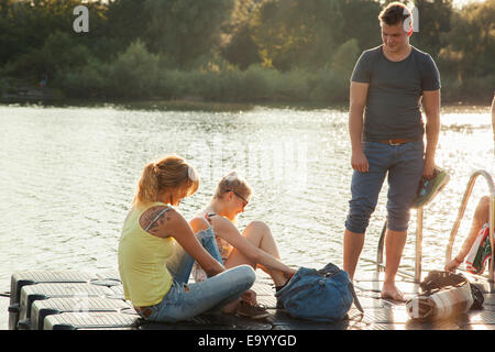 Trois jeunes amis adultes attacher ses lacets sur Riverside pier Banque D'Images