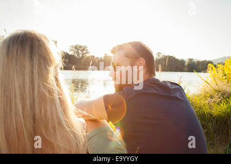 Young couple sitting on riverbank Banque D'Images