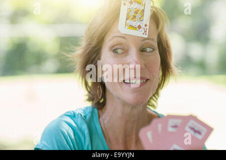 Young woman playing cards, un jeu de carte collée sur son front Banque D'Images