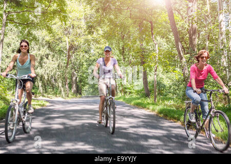 Trois mature woman riding bicycles le long de routes de campagne Banque D'Images