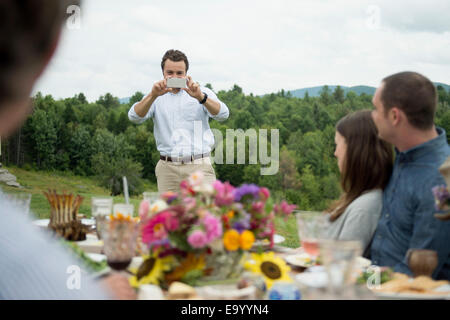 Jeune homme de prendre photo de famille en plein air, repas Banque D'Images