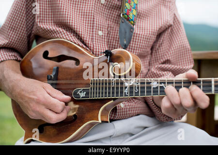 Homme mûr jouant de la mandoline, mid section, close-up Banque D'Images