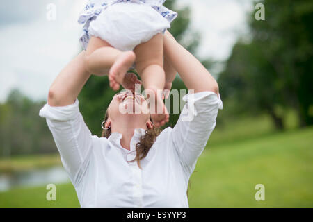 Mid adult woman holding baby girl dans l'air, à l'extérieur Banque D'Images