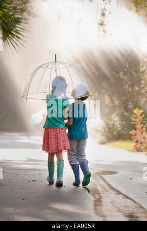 Vue arrière du garçon et fille exerçant son parapluie sur street Banque D'Images