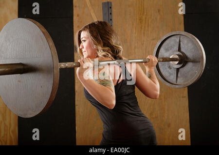 Jeune femme barbell levage in gym Banque D'Images