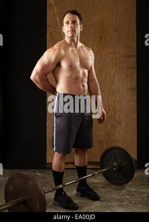 Portrait of mid adult male musculaire avec l'haltérophile barbell in gym Banque D'Images