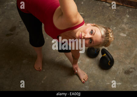 Mid adult woman lifting kettlebells in gym Banque D'Images