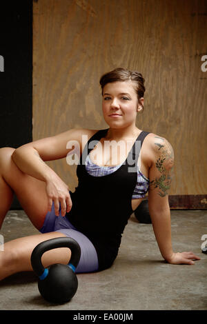 Portrait of young woman sitting on floor in gym Portrait of young woman sitting on floor in gym