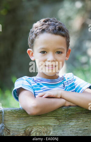 Portrait of boy leaning on jardin clôture Banque D'Images