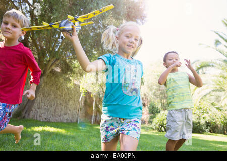 Trois enfants dans le jardin en marche avec toy airplane Banque D'Images