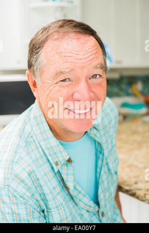Homme mûr assis dans la cuisine Banque D'Images