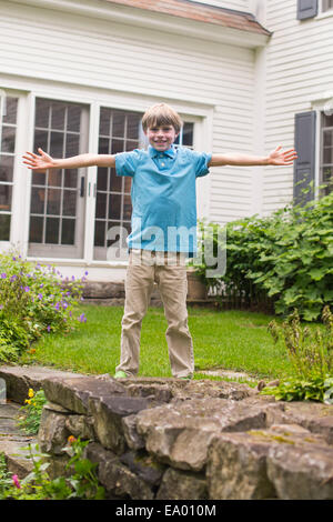 Portrait de jeune garçon au jardin, arms outstretched Banque D'Images