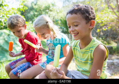 Trois enfants en jardin eating ice lollies Banque D'Images