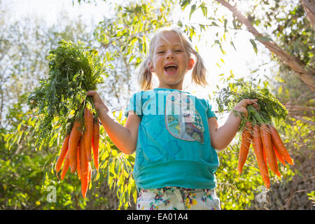 Portrait of Girl in garden holding up bouquets de carottes Banque D'Images
