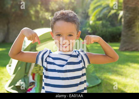 Portrait of boy in garden flexing muscles Banque D'Images