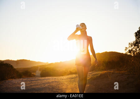 Female jogger de boire à la lumière du soleil, Poway, CA, USA Banque D'Images