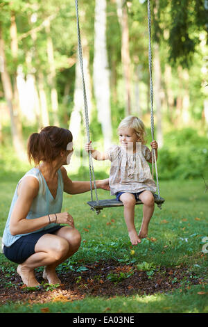 Mid adult mother and toddler fille jouer sur balançoire Banque D'Images