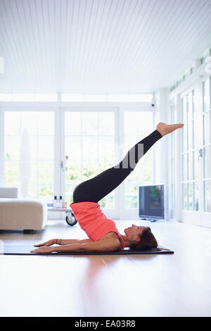 Mid adult woman lying on retour la pratique du yoga dans la salle de séjour Banque D'Images