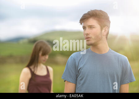 Jeune couple standing apart together in rural landscape sous bright sunny sky Banque D'Images