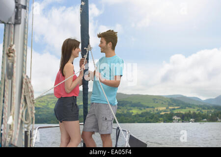 Jeune couple debout sur arc d'yacht de voile sur le lac sous le soleil Banque D'Images