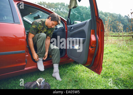 Man sitting in car mettre des chaussettes sur Banque D'Images