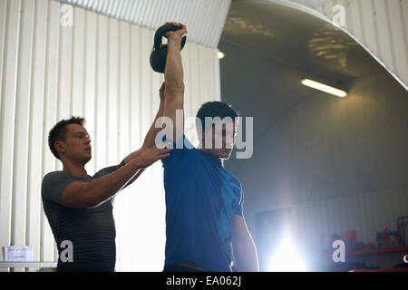 Coaching formateur homme avec kettlebell in gym Banque D'Images