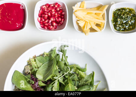 Salade de roquette avec graines de grenade et de la sauce, sauce pesto et couper l'avocat dans des bols sur fond blanc Banque D'Images