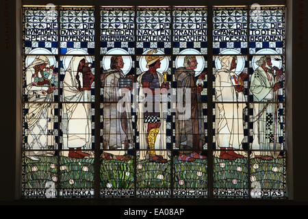 Vitrail 'Les sept oeuvres de miséricorde corporelle' conçu par l'artiste autrichien Koloman Moser (1907) dans l'Église Steinhof (Kirche am Steinhof) à Vienne, Autriche. Ancien Testament et saints personnages sont représentés dans le vitrail de gauche à droite : Saint Elisabeth de Hongrie, Rebecca, Saint Bernard, Saint Martin de Tours, Saint Jean de Dieu, Saint Jean de Matha et Tobias. Banque D'Images