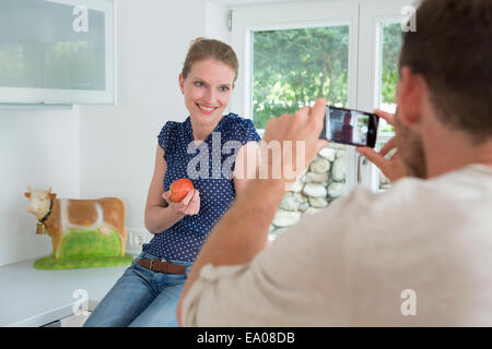 Man photographing woman with camera phone Banque D'Images