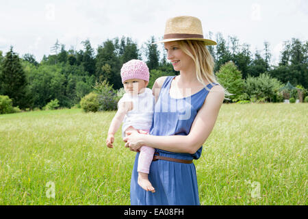 Mother holding baby daughter in field Banque D'Images