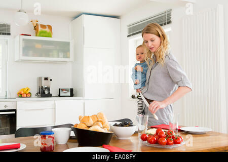 Réglage de la table de cuisine tout en tenant sa petite fille Banque D'Images