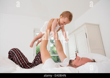 Père jouant avec sa petite fille sur le lit