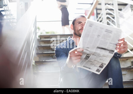 La lecture des journaux d'affaires on staircase Banque D'Images