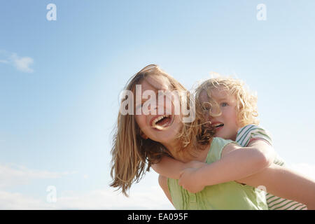 Low angle view of girl giving soeur piggy back at coast Banque D'Images