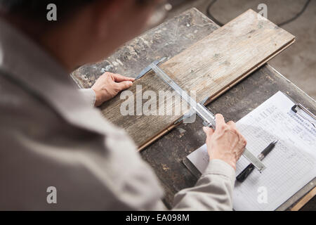 Carpenter measuring planche en bois avec pied à coulisse en usine, Jiangsu, Chine Banque D'Images