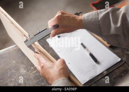 Carpenter measuring planche en bois avec pied à coulisse en usine, Jiangsu, Chine Banque D'Images