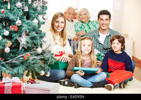 Family celebrating christmas avec trois générations sous tree with gifts Banque D'Images