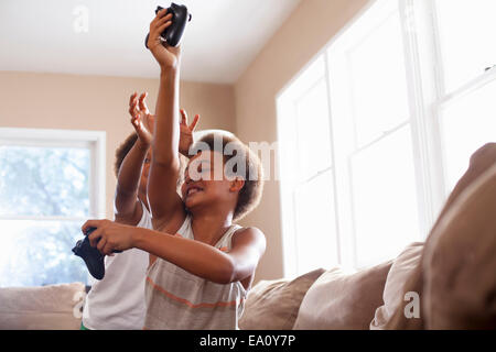 Deux frères playfighting sur les contrôleurs de jeu dans la salle de séjour Banque D'Images