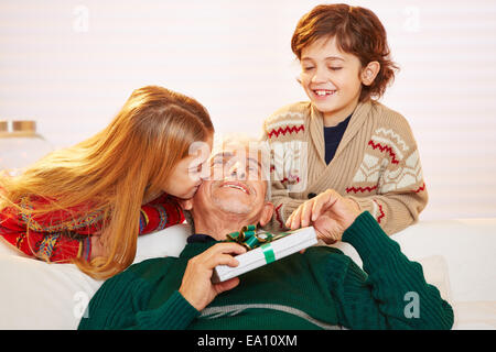 Girl kissing grand-père sur la joue avec un cadeau à Noël Banque D'Images