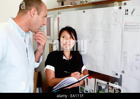 Homme et femme architects looking at blueprints in office Banque D'Images