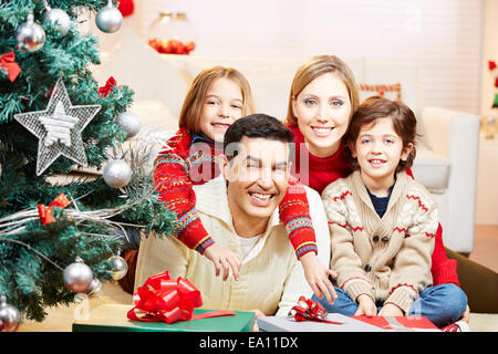 Une famille heureuse avec des enfants assis à Noël avec des cadeaux et des arbres Banque D'Images