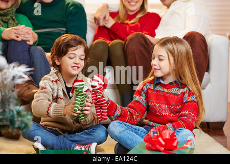 Deux enfants jouant avec des cadeaux à la veille de Noël et la famille est à regarder Banque D'Images