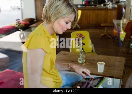 Mid adult woman using digital tablet in cafe Banque D'Images