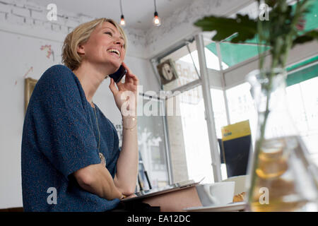 Mid adult woman on cell phone in cafe Banque D'Images