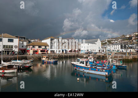 Les nuages de tempête et un arc-en-ciel sur les bateaux de pêche à Mevagissey harbour, Cornwall. Banque D'Images